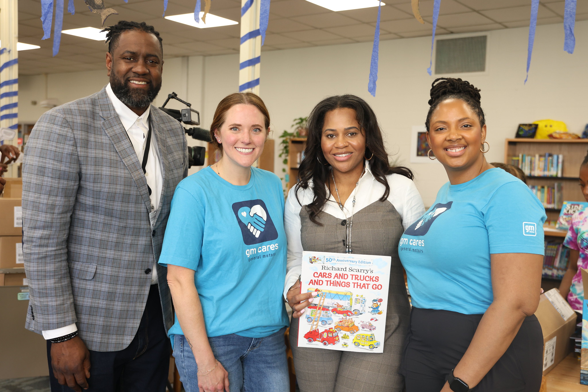 Four volunteers and school partners smiling together inside a Detroit school