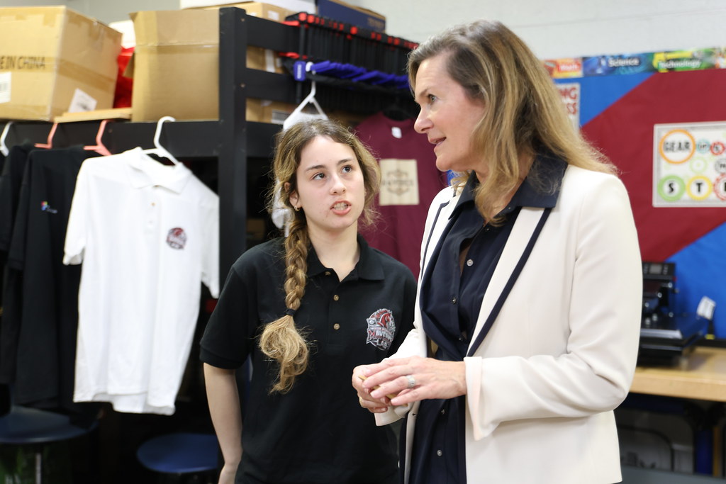 A student demonstrates custom shirt pressing for a guest on opening day