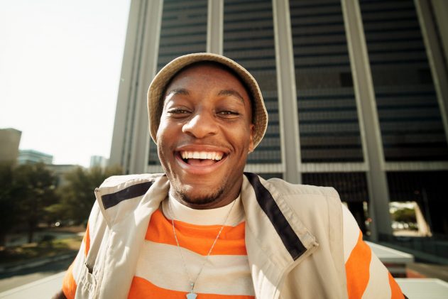 Black man, portrait and fashion with smile outdoor for streetwear, stylish clothes and youth culture. Happy, male person and travel for trendy aesthetic, urban commute and retro outfit of accessories.